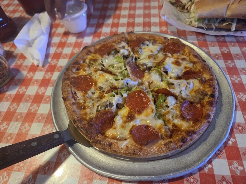 A salad and fries served beside pizza.